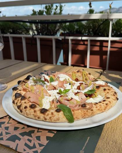 Pizza com mortadela e burrata em terraço com vista para o lago
